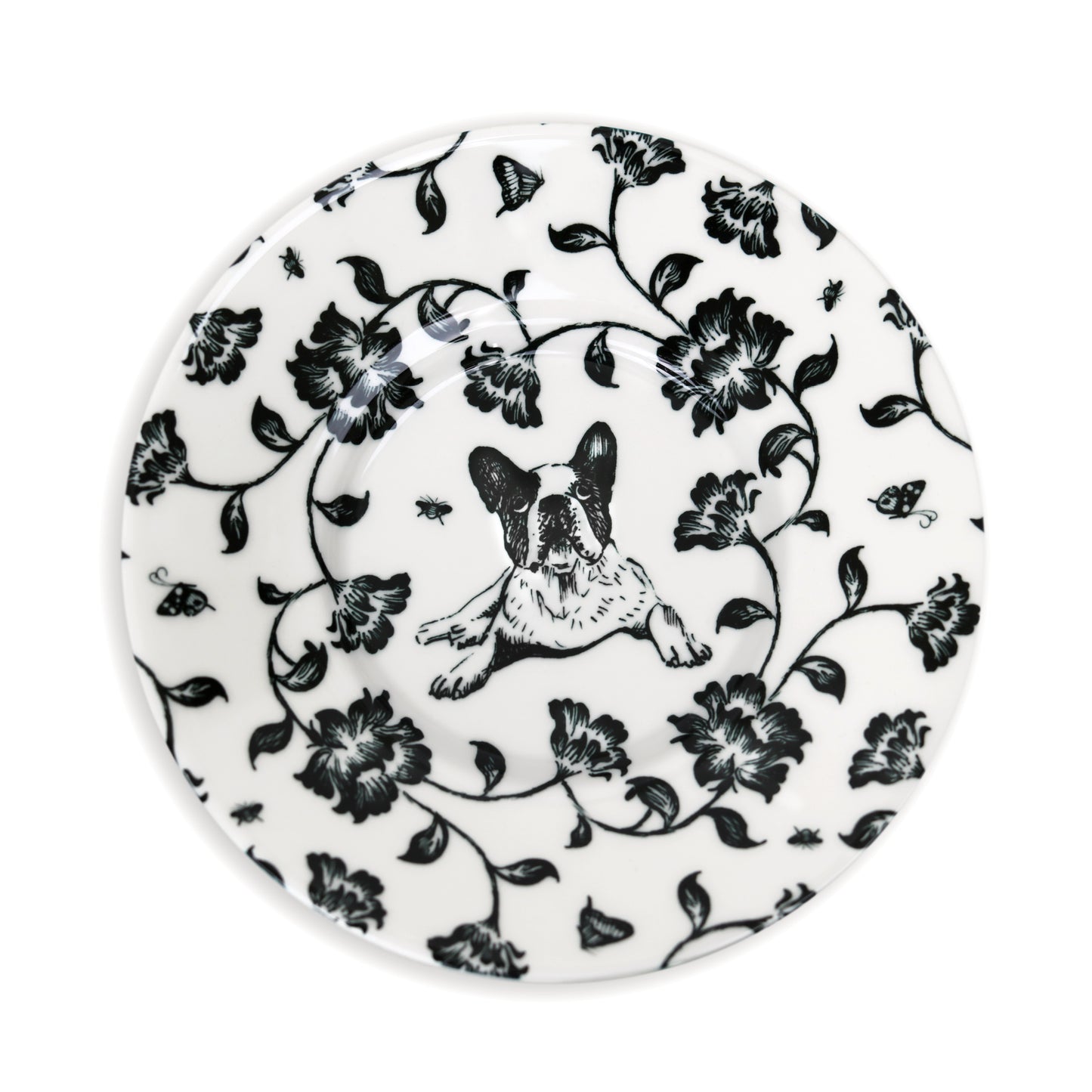 Close-up of black and white saucer design featuring dog and flower illustration.