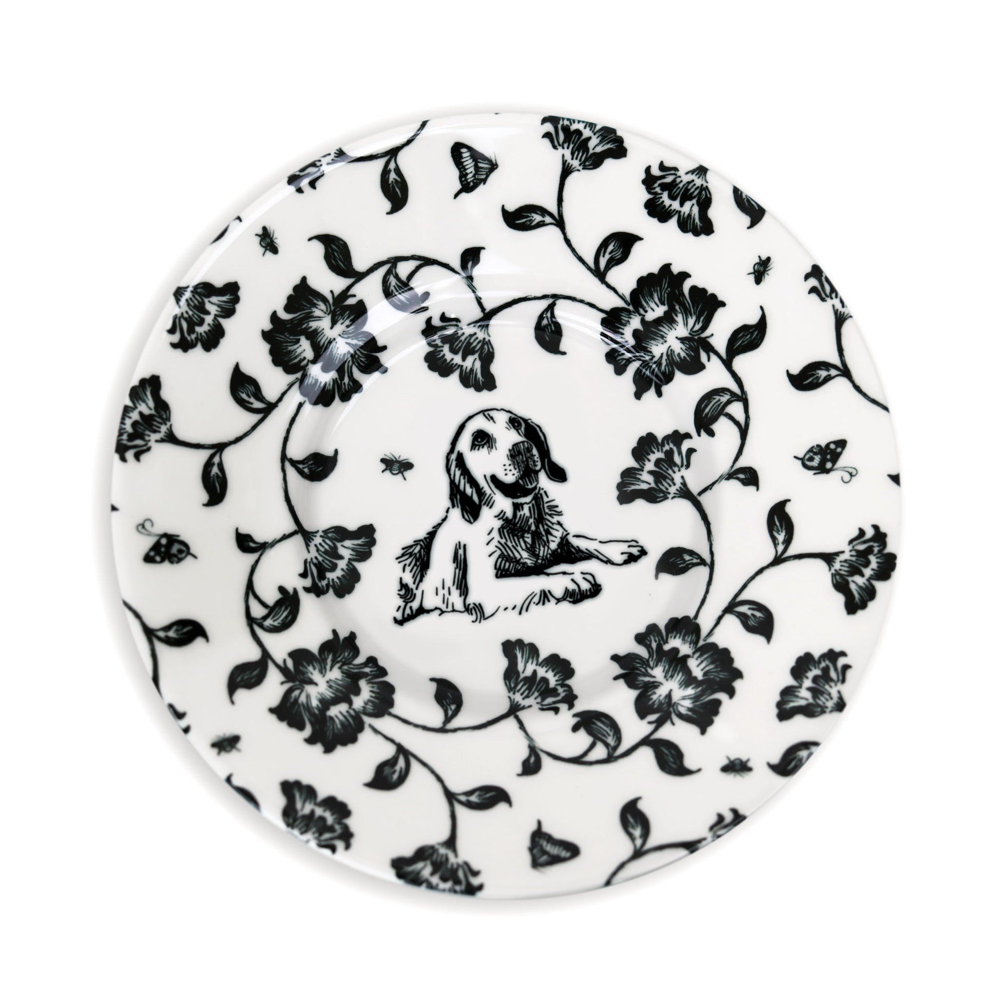 Close-up of black and white saucer design featuring dog and flower illustration.