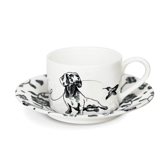 A black and white cup and saucer featuring a dachshund design, elegantly displayed against a neutral background.