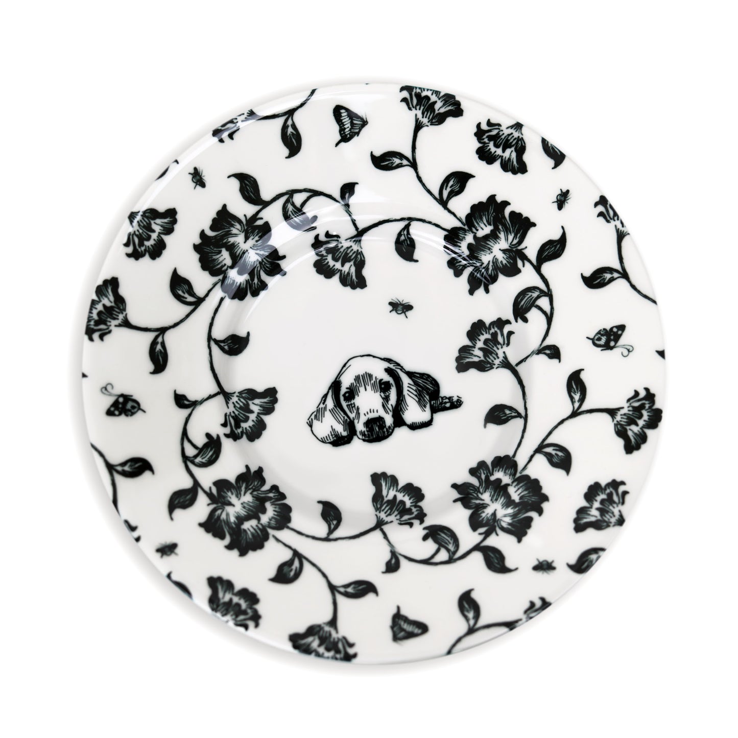 Close-up of black and white saucer design featuring dog and flower illustration.