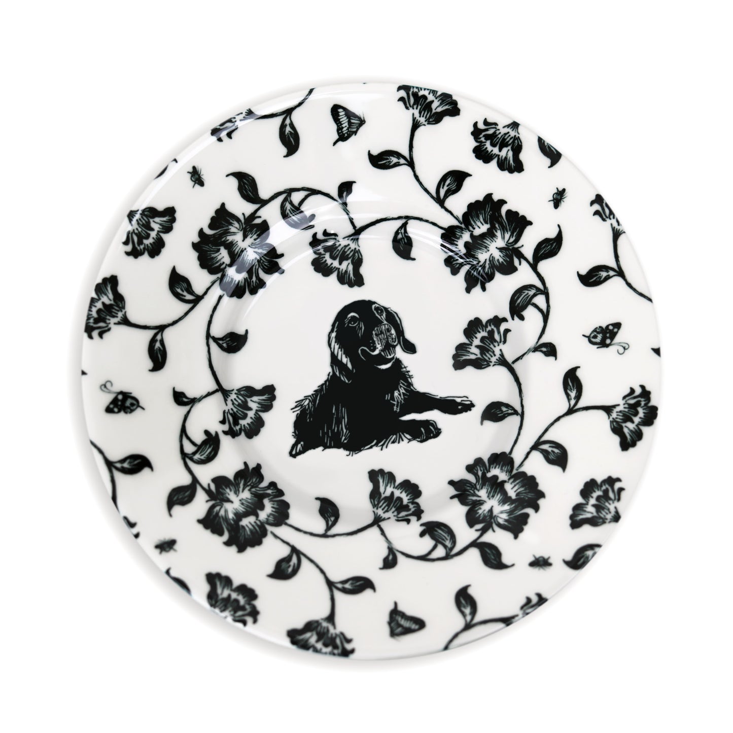 Close-up of black and white saucer design featuring dog and flower illustration.